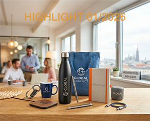 Tasse, Isolierflascheu und andere Werbeartikel auf einem Holztisch, im Hintergrund ein Büro und Aussicht einer Stadt wenn man aus dem Fenster sieht